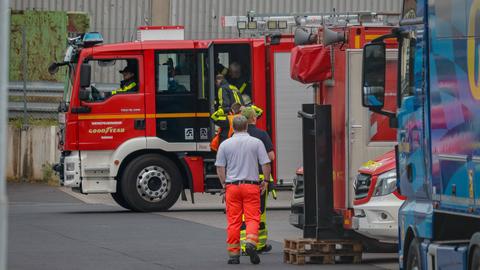 Einsatzkräfte der Feuerwehr steigen in ein Feuerwehrauto ein