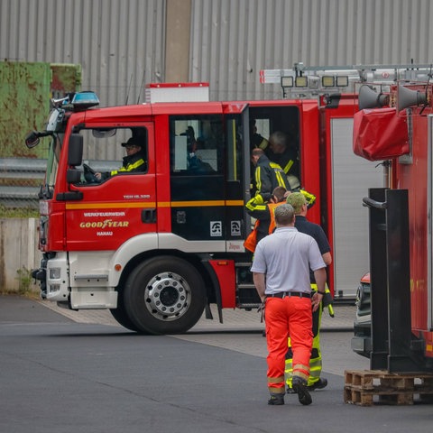 Einsatzkräfte der Feuerwehr steigen in ein Feuerwehrauto ein