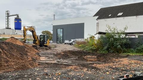 Bombenfund in Hanau - ein Bagger steht auf einer Baustelle - davor ein ausgehobenes Loch