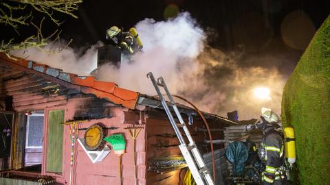 Feuerwehrleute auf dem Dach der brennenden Hütte