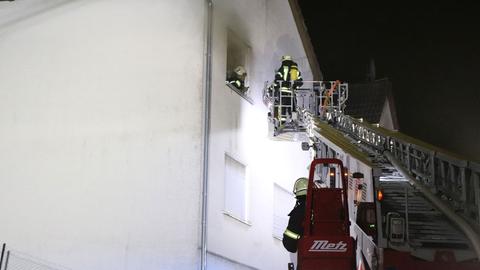 Feuerwehrleute auf einer Drehleiter, im Hintergrund das Haus.