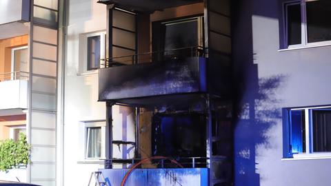 Ein Balkon einer Wohnung - dahinter ist alles innerhalb der Wohnung verkohlt und schwarz verbrannt.