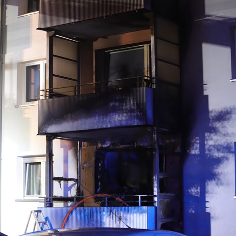 Ein Balkon einer Wohnung - dahinter ist alles innerhalb der Wohnung verkohlt und schwarz verbrannt.