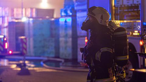 Ein Feuerwehrmann steht in voller Schutzmontur vor dem betroffenen Haus. 