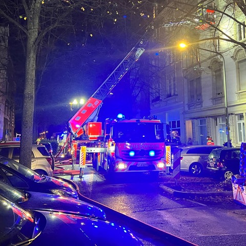 Ein Feuerwehrauto steht in einer Straße in der Dunkelheit und hat einen Einsatz.