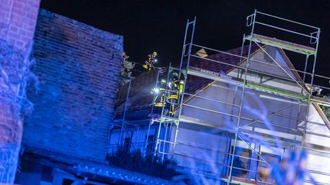 Feuerwehrleute stehen auf einem Gerüst am Dach.