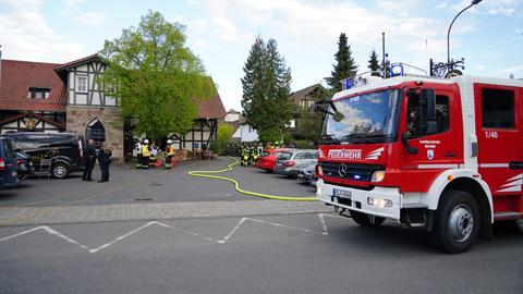 Ein Feuerwehrauto steht im Hof eines Restaurants. Löschschläuche führen Richtung Gebäude.