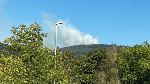 Von der Straße aus sind große graue Wolken über dem Wald bei Königstein zu sehen.