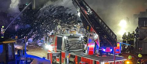 Feuerwehrmänner vor einem großen, schwelenden Schuttberg