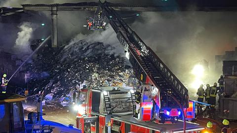 Feuerwehrmänner vor einem großen, schwelenden Schuttberg