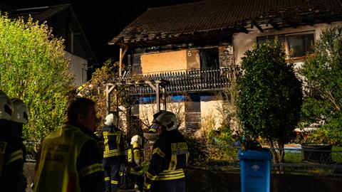 Feuerwehrkräfte vor dem Haus in Lützelbach, das deutliche Brandspuren aufweist.