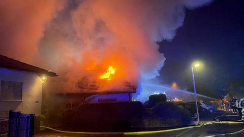 Feuerwehr mit Löschschlauch an brennendem Dach.