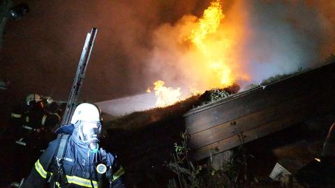 Ein Feuerwehrmann steht vor der brennenden Blocksauna.