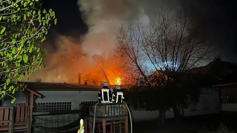 Zwei Feuerwehrleute vor der Scheune, die in Flammen steht. 