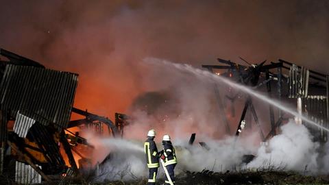 Zwei Feuerwehrleute kämpfen gegen den Scheunenbrand in Eiterfeld