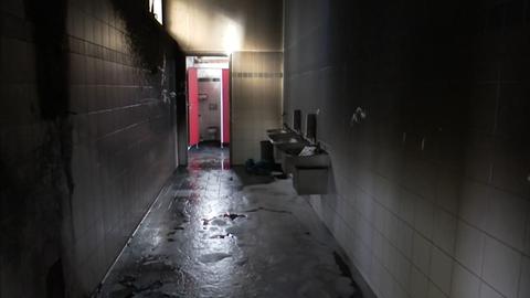Eine Schultoilette ist nach einem Brand demoliert, verrußt und schwarz. 