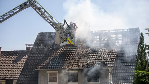 Feuerwehrleute löschen den qualmenden Dachstuhl von einer Drehleiter aus.