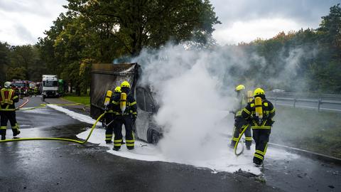 Feuerwehrleute löschen den brennenden Wagen. 