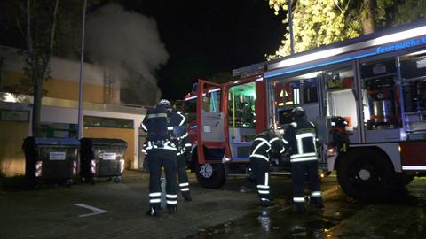 Feuerwehrleute stehen vor dem Bürgerhaus, aus dem Rauch aufsteigt.