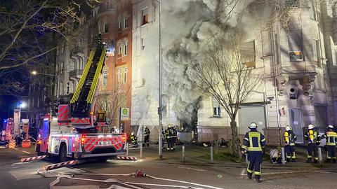 Rauch qualmt aus einem Mehrfamilienhaus - die Feuerwehr ist mit einer Drehleiter im Einsatz