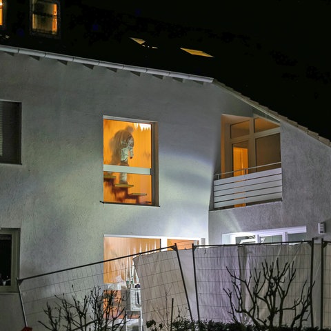 Ein Mitarbeiter der Spurensicherung im Treppenhaus eines Hauses, von außen fotografiert