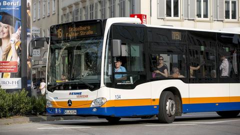 Fahrender Stadtbus mit Busfahrer und Insassen.