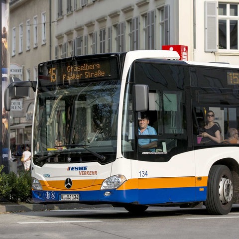Fahrender Stadtbus mit Busfahrer en Insassen.