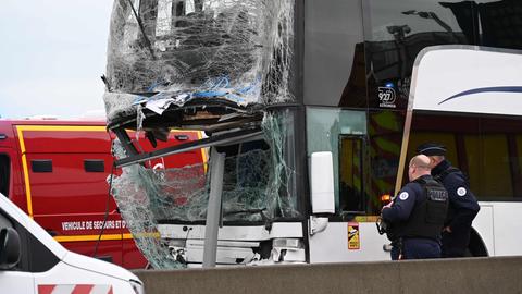 Französische Polizeibeamte stehen neben einem beschädigten Bus.