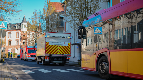 Eine Straße, rechts im Bild ein Bus der Hanauer Stadtbahn, links daneben stehen Rettungswagen.