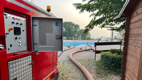 Feuerwehr pumpt Wasser zum Löschen aus dem Freibad im Butzbach