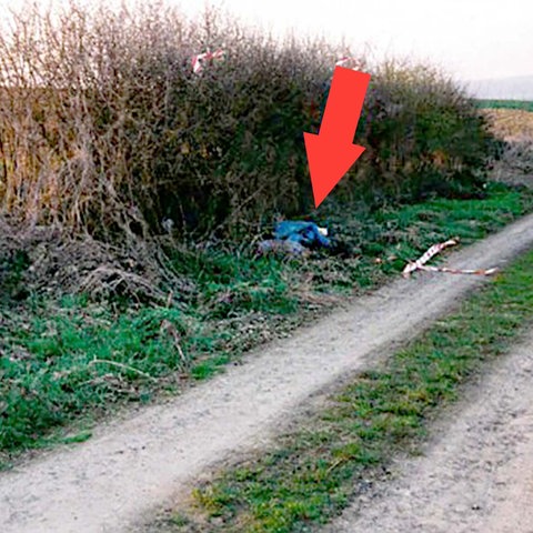 Foto eines Feldwegs in der Landschaft. Am Rand leicht verdeckt ein blauer Müllsack (in dem der Leichnam verborgen war). Ein roter Pfeil markiert in dem Bild die Stelle. 