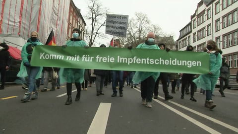 Eine Gruppe von Menschen zieht mit einem Transparent durch eine Straße.