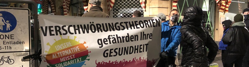 Ein Demonstrant hält ein Banner mit der Aufschrift "Verschwörungstheorien gefährden Ihre Gesundheit."