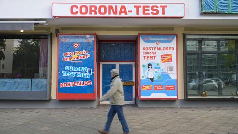 Mann läuft vor Geschäft entlang, oben den Schrifzug "Corona Test"