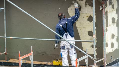 Mann verputzt gedämmten Neubau