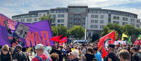 Menschen mit Flaggen und einem Banner mit der Aufschrift "No more war" stehen auf einem Platz in Kassel.