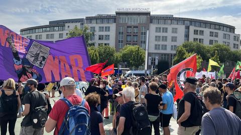 Menschen mit Flaggen und einem Banner mit der Aufschrift "No more war" stehen auf einem Platz in Kassel.
