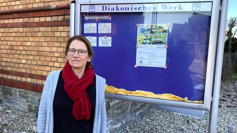 Frau mit rotem Schal vor Schaukasten Diakonisches Werk