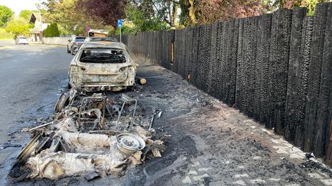 Zwei der drei zerstörten Autos - der Zaun nebenan ist auch durchs Feuer beschädigt. 