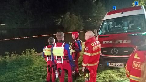 Feuerwehrleute stehen am Ufer eines Sees