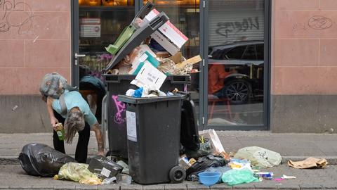 Obdachloser neben übervoller Mülltonne im Frankfurter Bahnhofsviertel