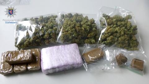 Große Mengen verschiedener illegaler Drogen liegen verpackt in Plastikfolie auf einem Tisch.