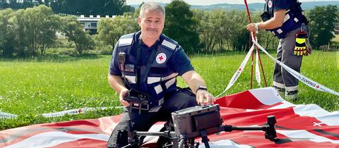 Ein Rettungssanitäter vom Deutschen Roten Kreuz hantiert an der neuen Drohne für Notfalleinsätze und hockt dabei auf dem Boden. 