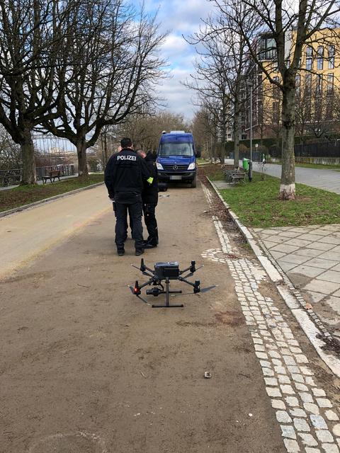 Polizeibeamte auf einem Weg am Tatort mit einer Drohne