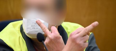 Der Angeklagte zeigt zu Prozessbeginn in Frankfurt seine Mittelfinger.