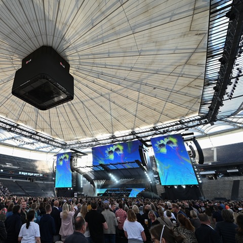 Im Frankfurter Stadion schauen tausende Menschen auf eine Bühne, die auf dem Rasen aufgebaut ist.