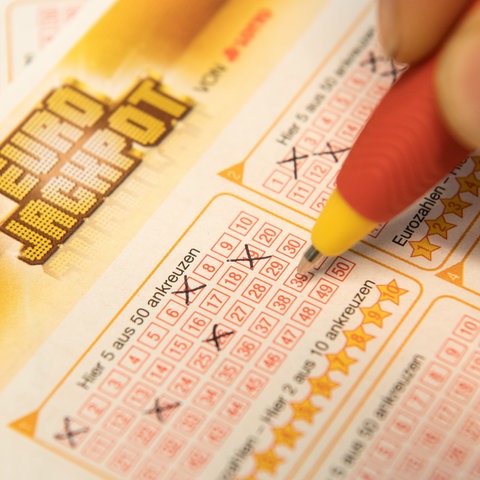 Mit einem Stift werden Zahlen in Eurojackpot-Schein angekreuzt