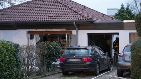 Ein beschädigtes Haus, davor parkende Fahrzeuge