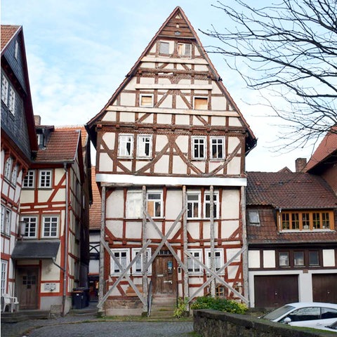 Bildkombination: links Screenshot eines Webshops mit dem Foto eines Modellbauhauses, rechts verfallendes und abgestützes Fachwerkhaus in einer Altstadt. 