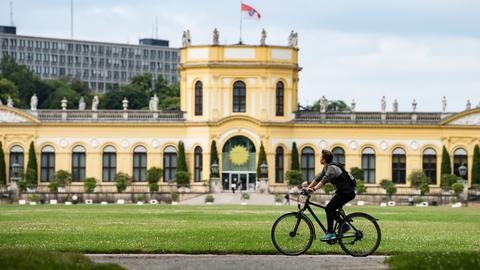 Radfahrer in der Karlsaue fährt an der Orangerie vorbei 